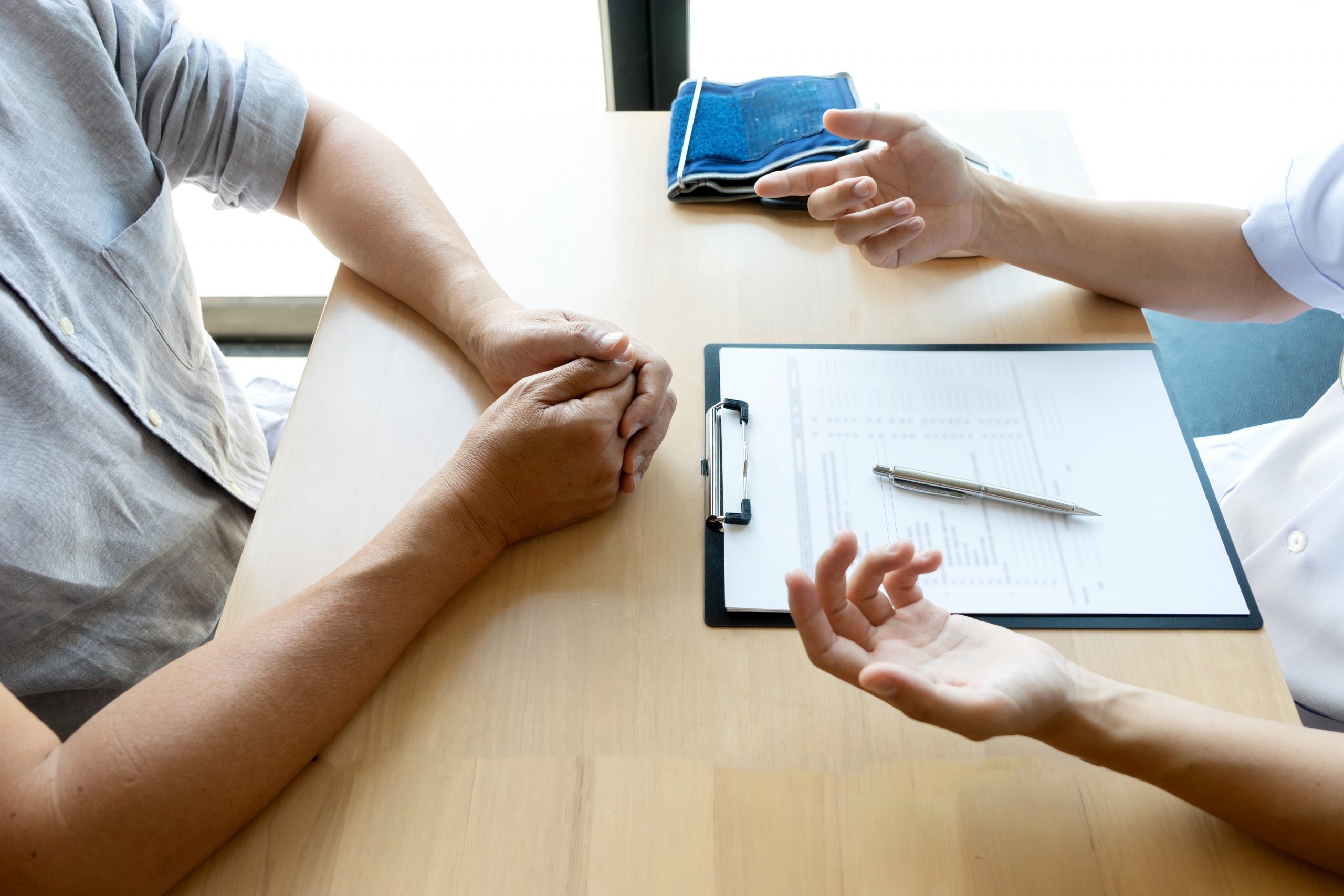 professional doctor sit at the table and talk about health care to the patient, on the table there are bottle of medicine.
